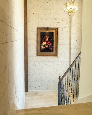 Una escalera con un cuadro enmarcado de un violinista, una pared con textura y una barandilla de metal.