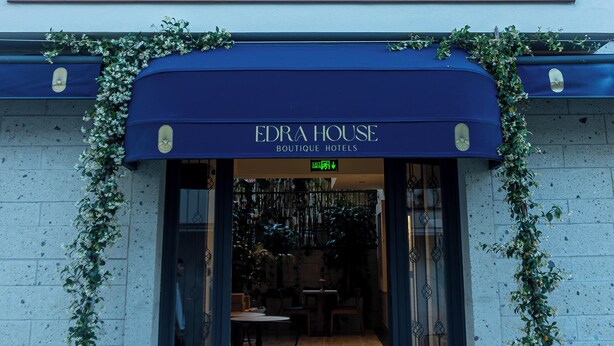 A boutique hotel entrance with a dark blue awning, a sign reading 'EDRA HOUSE BOUTIQUE HOTELS,' and a view into the interior. - EDRA HOUSE (Cesme)