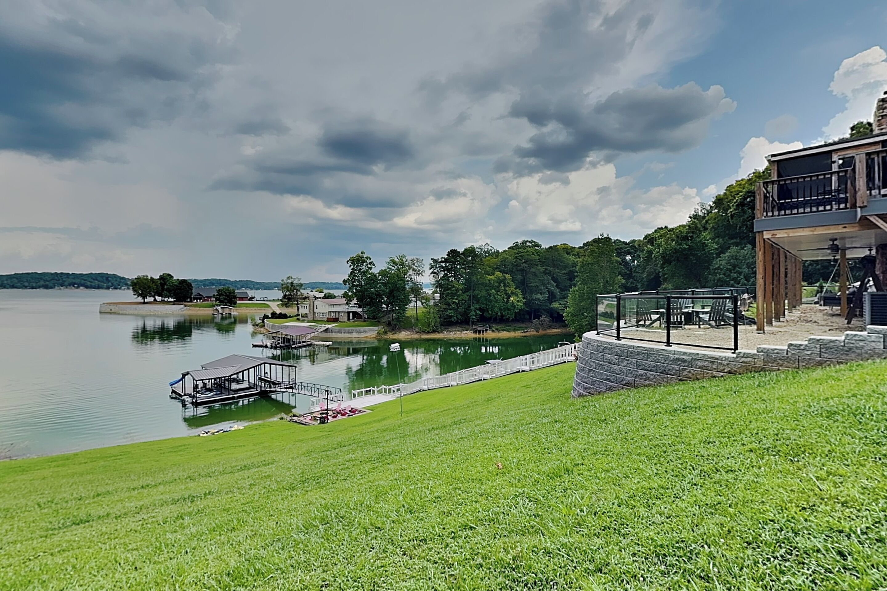 A lakeside property with a grassy area, a dock, and a building with outdoor seating.