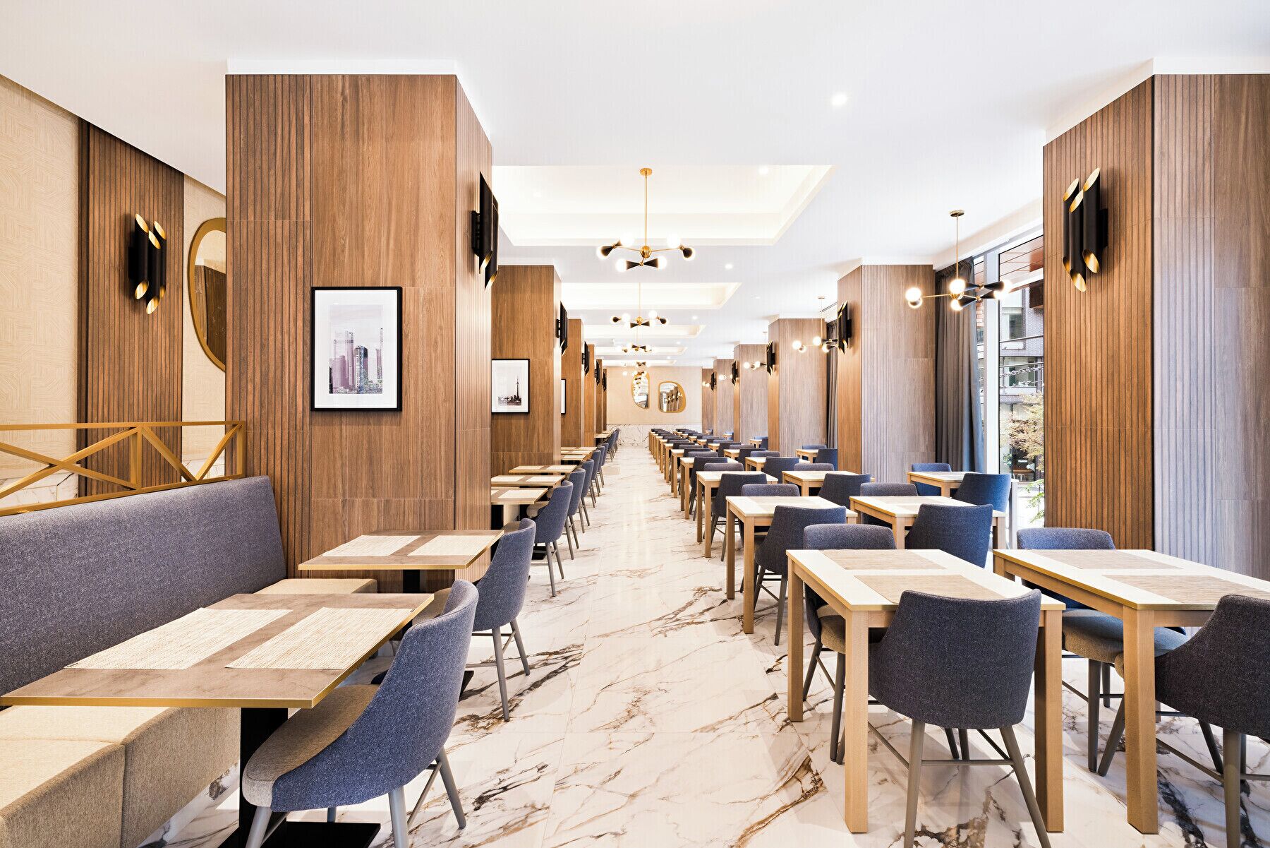 A modern restaurant with wooden paneling, marble flooring, and a long counter with blue chairs.
