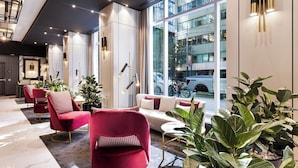 Um hall de hotel moderno com área de estar, grandes janelas e vista para a cidade.
