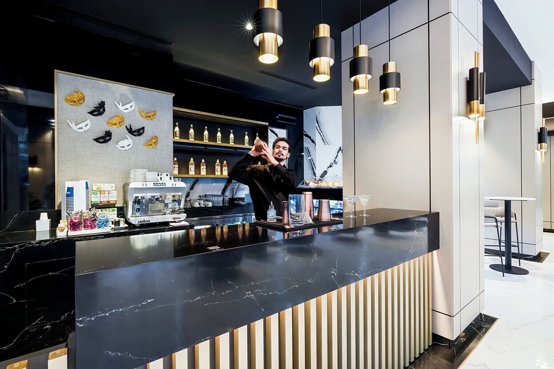 Een moderne bar met een marmeren aanrecht, barstoelen en een barman.