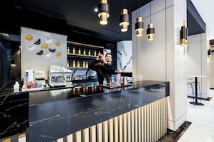 Een moderne bar met een marmeren aanrecht, barstoelen en een barman.