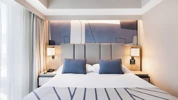 A modern hotel room with a large bed, two bedside lamps, and a city view.