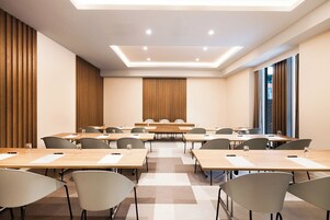 Een congrescentrum met meerdere tafels en stoelen, een modern plafond en grote ramen.