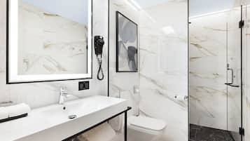 Een moderne badkamer met een marmeren wastafelmeubel, een douchecabine van glas en een toilet.
