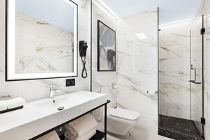 Een moderne badkamer met een marmeren wastafelmeubel, een douchecabine van glas en een toilet.