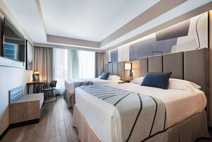 Een moderne hotelkamer met twee bedden, een bureau, een stoel en een televisie.