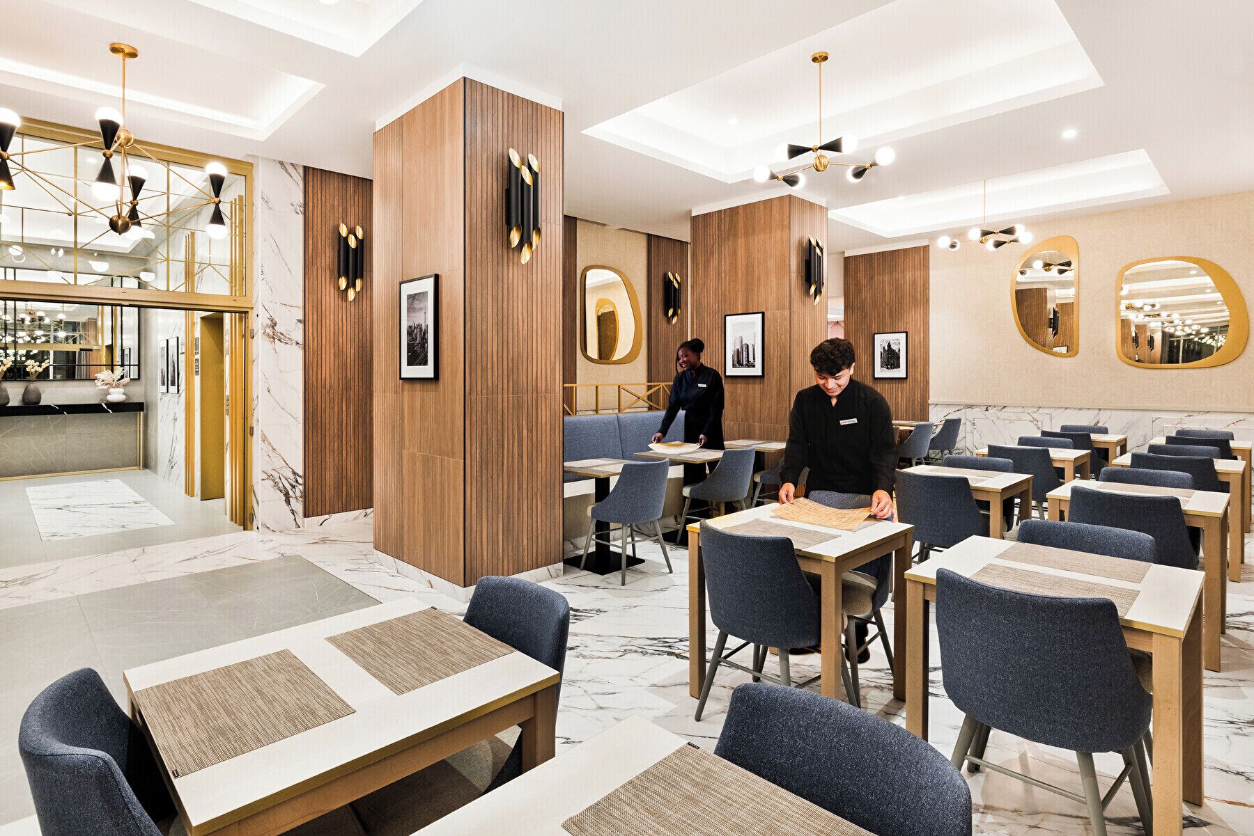 Un restaurante moderno con paneles de madera, suelo de mármol e iluminación contemporánea.