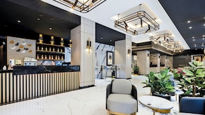 Um lobby moderno com área de bar, assentos e escadaria.