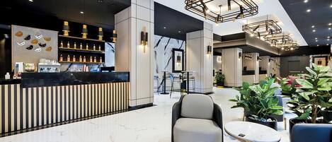 A modern lobby with a bar area, seating, and a staircase.