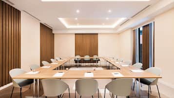 Un salón de conferencias con una larga mesa, sillas y un diseño moderno en el techo.