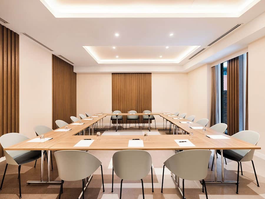 Un salón de conferencias con una larga mesa, sillas y un diseño moderno en el techo.