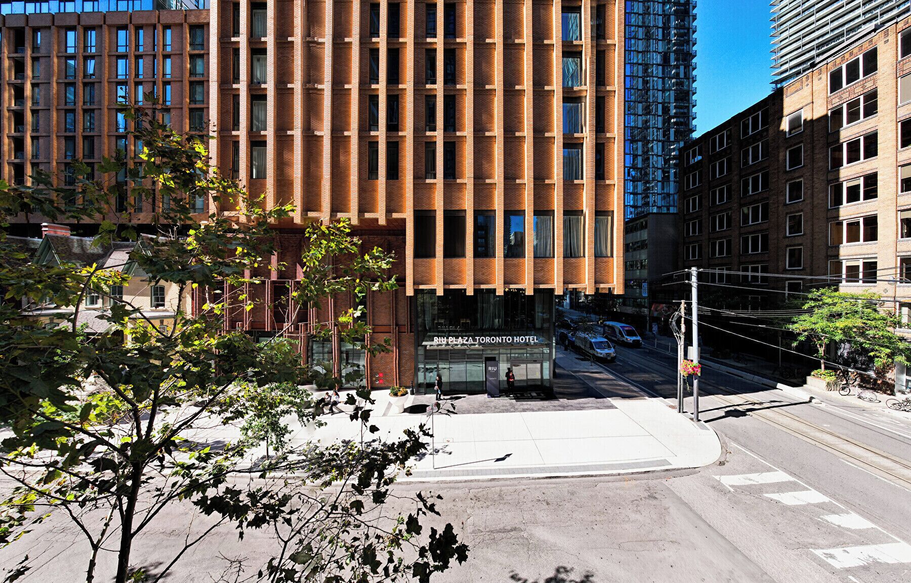 A modern hotel with a brick facade and large windows, located at a city intersection.