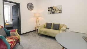 A living room with a sofa, a chair, a table, a floor lamp, and a clock on the wall.