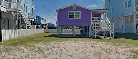 A beachfront property with a purple house, a white fence, and a sandy beach.
