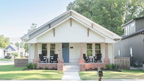 A single-story house with a front porch, two windows, and a door.