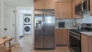 Una cocina compacta con un refrigerador de acero inoxidable, una cafetera y una estufa.