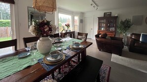 Ein Essbereich mit einem Holztisch, gedeckt für vier Personen, einer Blumenvase und einer Pendelleuchte.