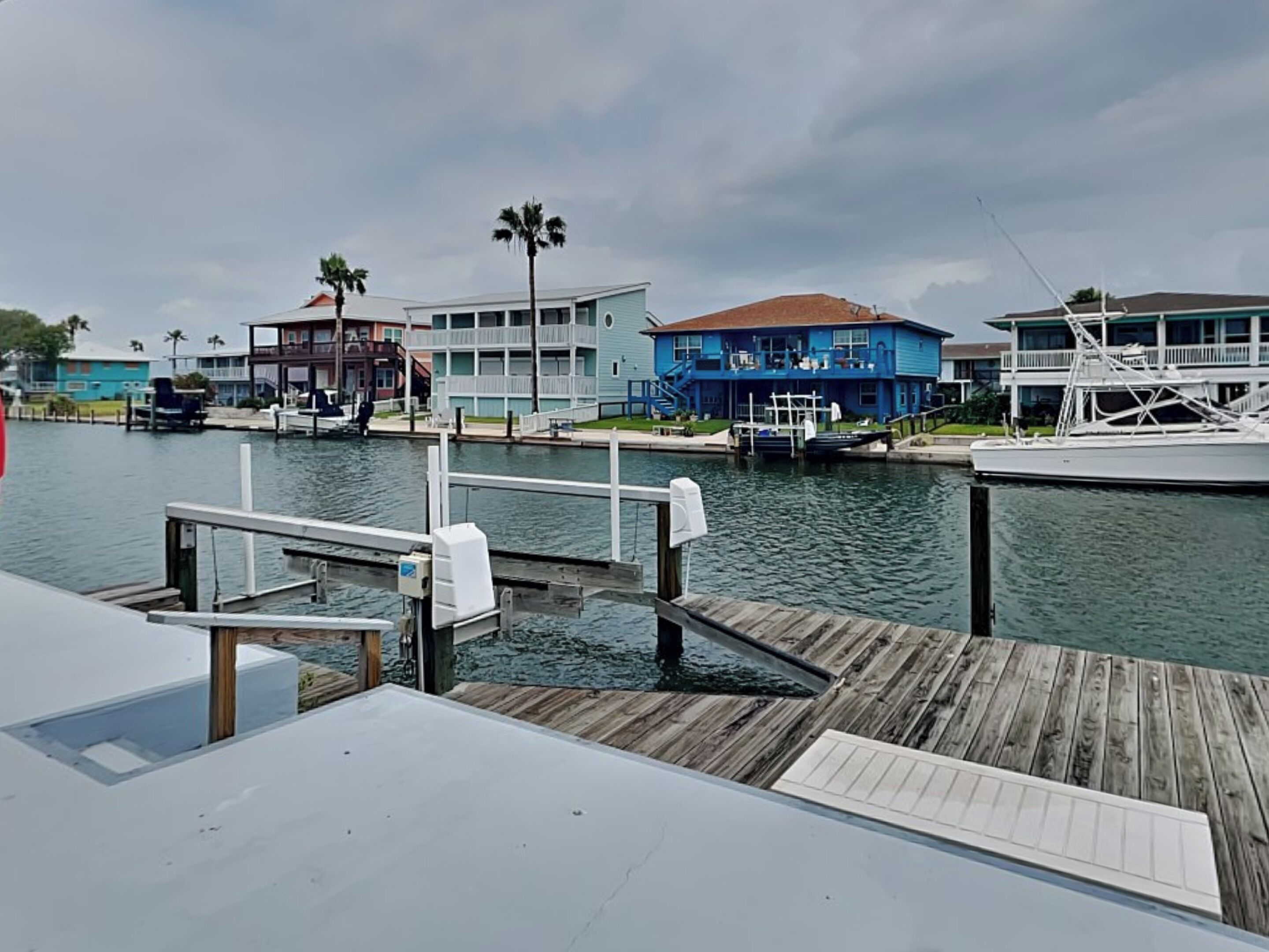 A waterfront property with a dock, a blue house, and a white building with a balcony.