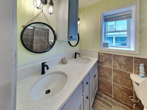 A bathroom with two sinks, a mirror, a window, and a toilet.