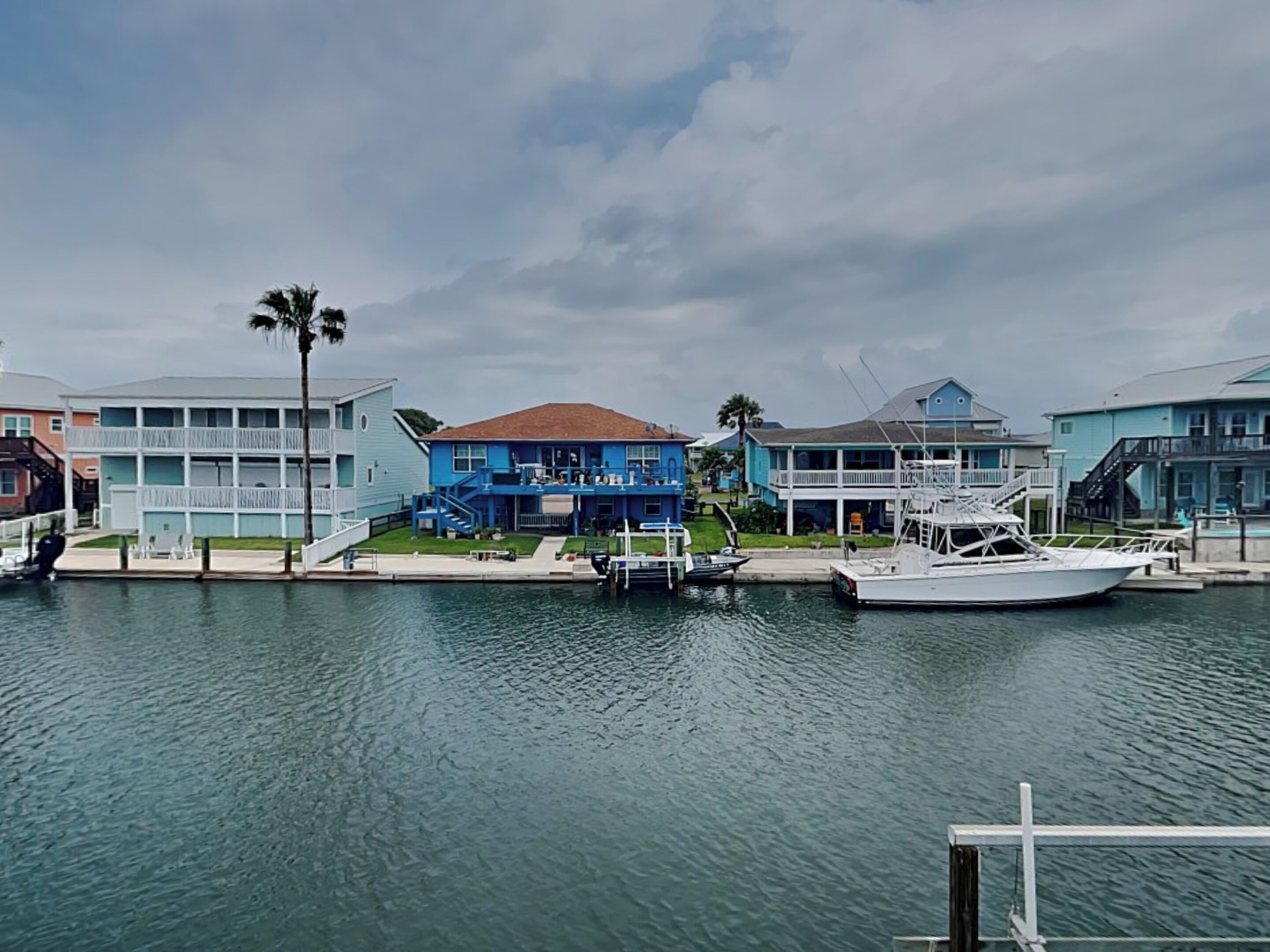 Une propriété située au bord de l’eau, dotée d’un quai, d’un bateau et d’un bâtiment bleu avec un toit marron.