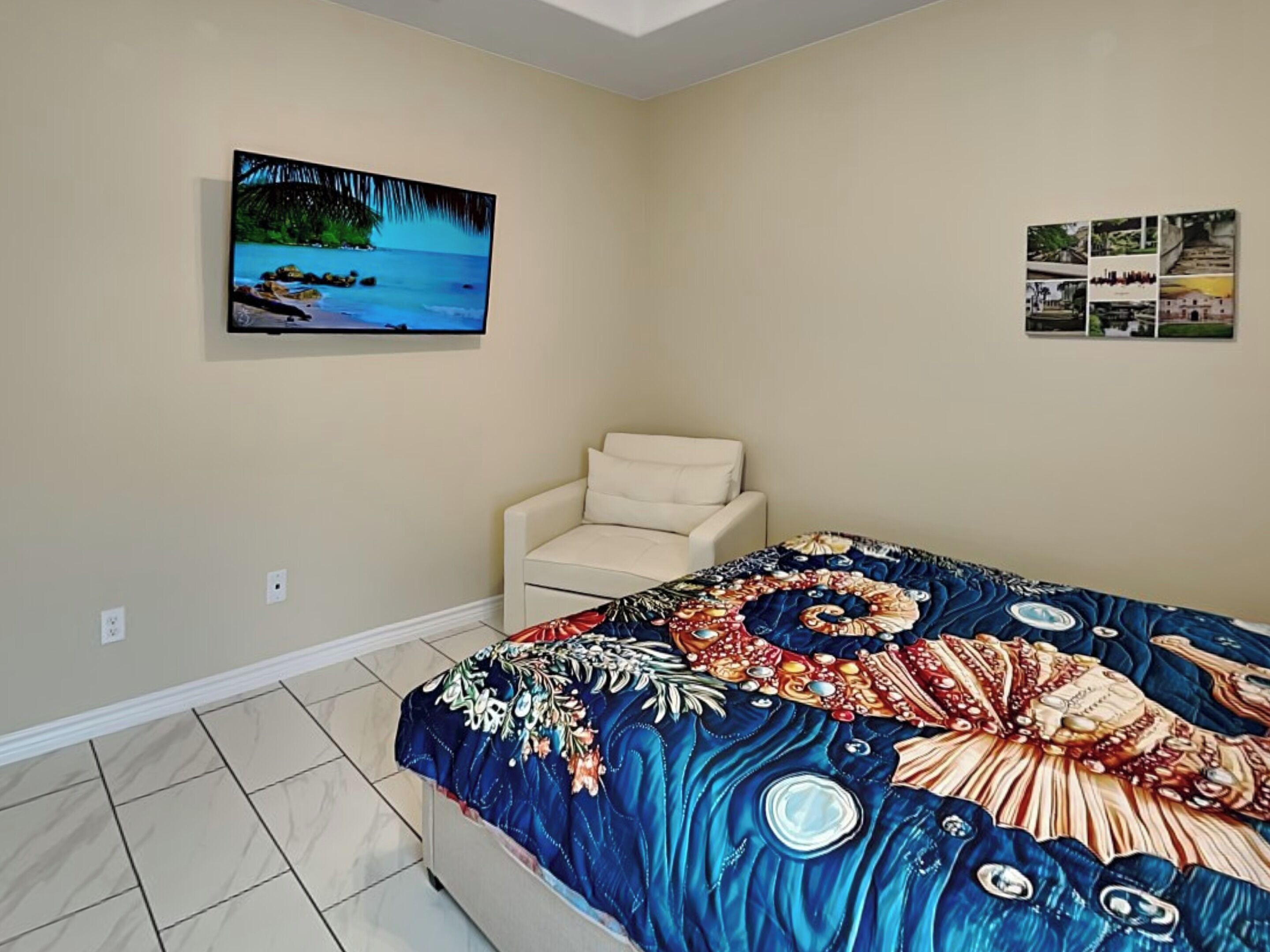 A bedroom with a bed, a chair, and a wall-mounted TV.