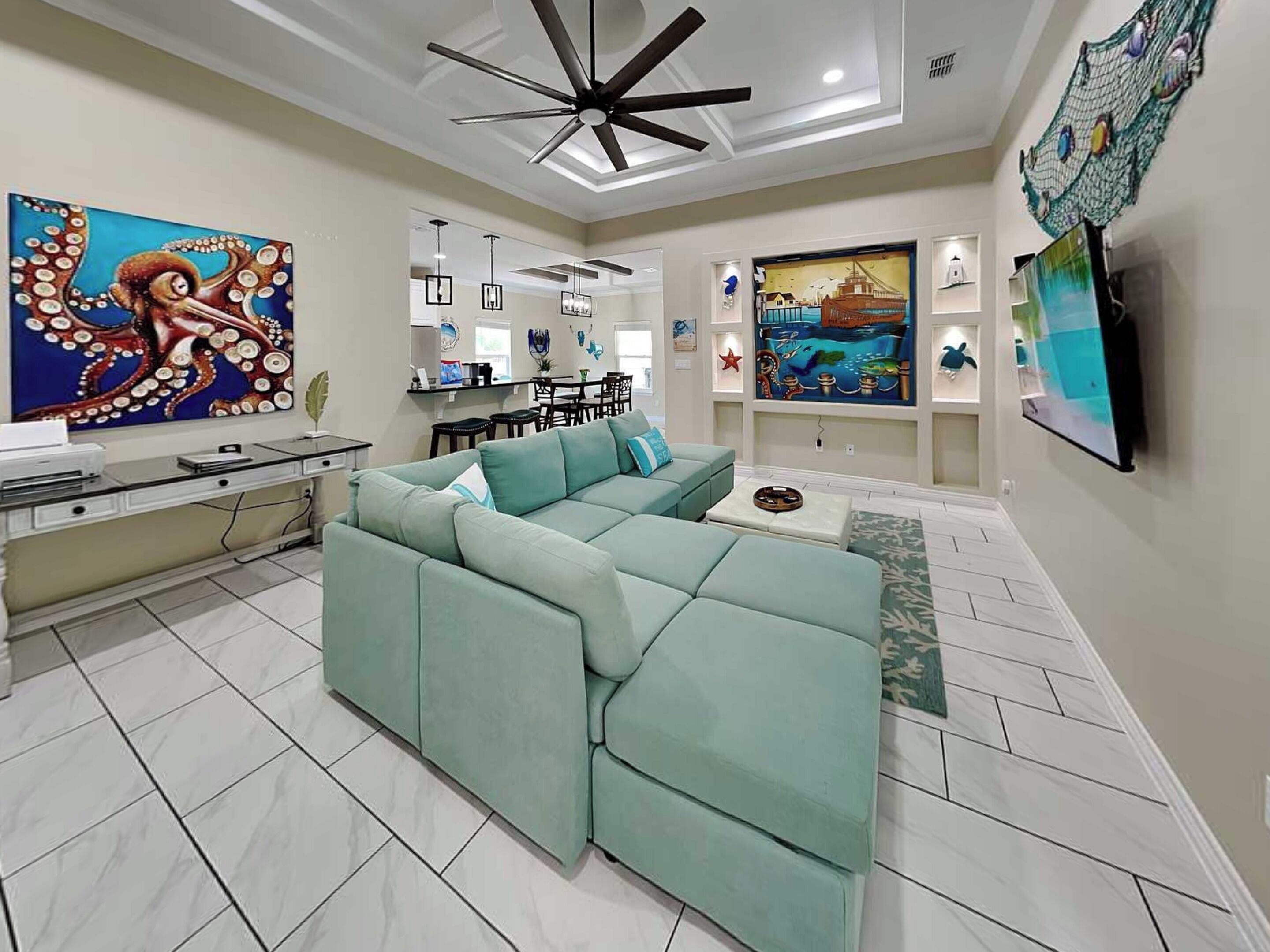 A modern living room with a sectional sofa, a dining area, and artwork on the walls.