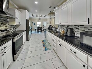 Una cocina moderna con armarios blancos, electrodomésticos de acero inoxidable y suelo de baldosas.