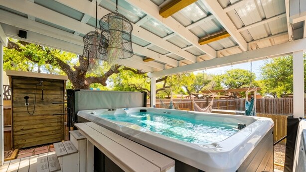 A hot tub with a wooden deck, a pergola overhead, and a wooden fence in the background. - Ferryman's Landing by Miss Kitty’s (Aransas Pass)