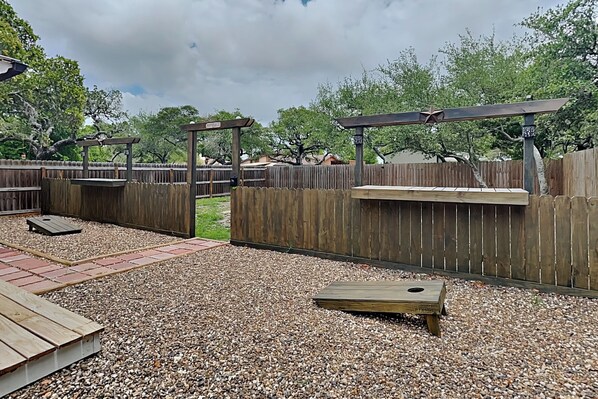 Un espace extérieur clos, doté d’un sol en gravier, de bancs en bois et d’une structure de pergola en bois.