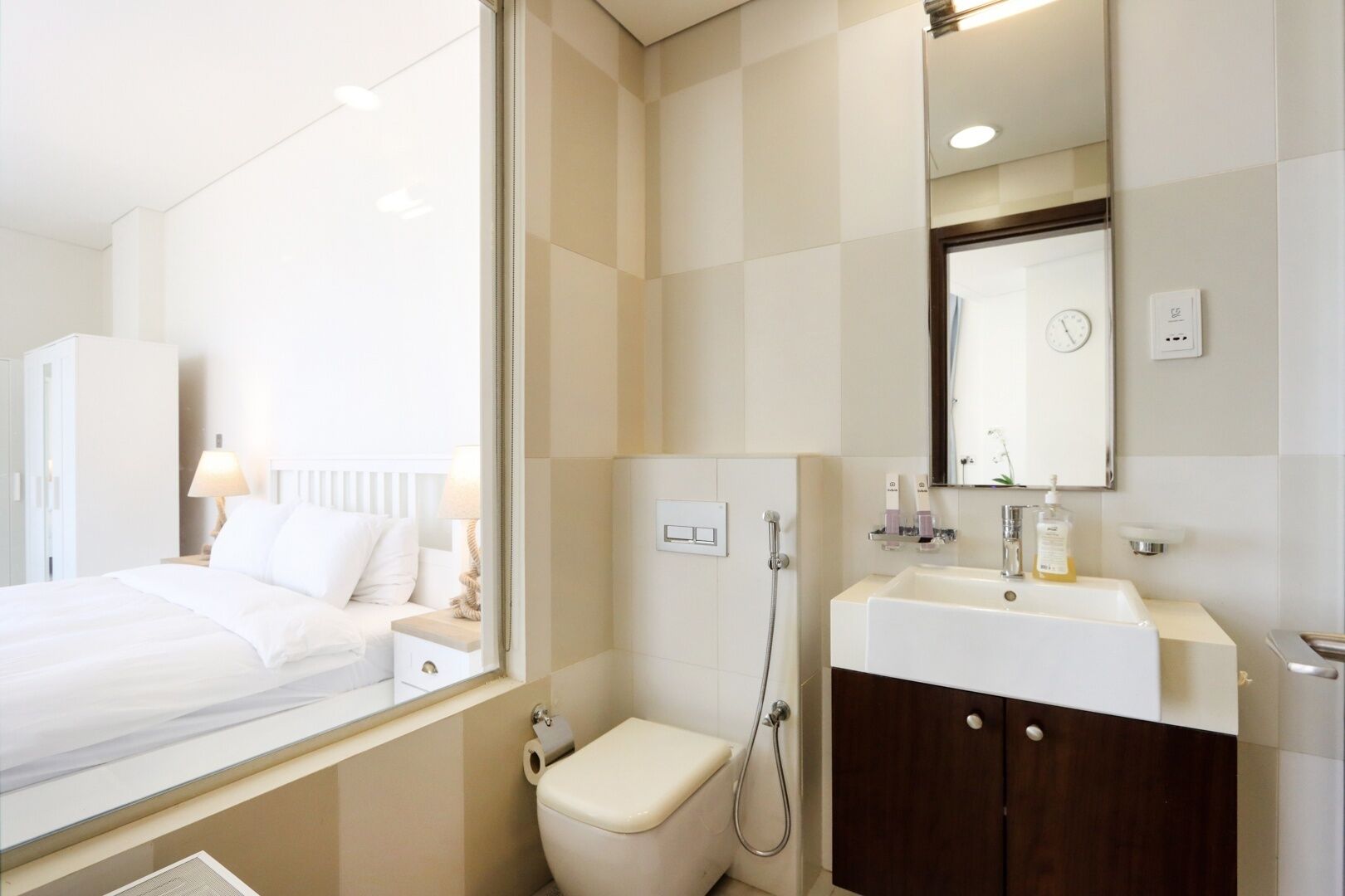 A hotel bathroom with a toilet, shower, sink, and mirror.