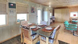 Un coin repas avec une table dressée pour quatre personnes, entourée de chaises en osier.