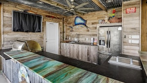 A rustic kitchen with a wooden countertop, a refrigerator, and a ceiling fan. - The Salty Dog at Copano Bay by Miss Kitty’s (Rockport)