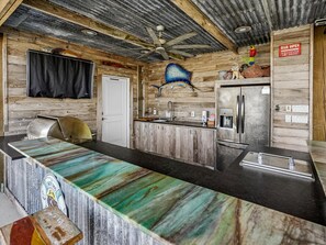 Eine rustikale Küche mit einer Holzausziehtheke, einem Kühlschrank und einem Deckenventilator.