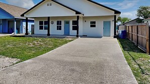 A two-story house with a front porch, a garage, and a fenced backyard. - Bayside Abode by Miss Kitty’s (Rockport)