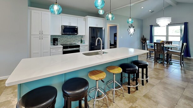 A modern kitchen with a large island, bar stools, and pendant lighting. - Bayside Abode by Miss Kitty’s (Rockport)