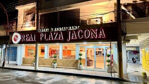 Restaurante llamado 'Great Plaza Jacona', con una entrada bien iluminada y plantas en macetas afuera.