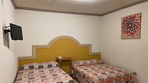 Una habitación con dos camas, cabecera, teléfono de pared y un adorno mural.