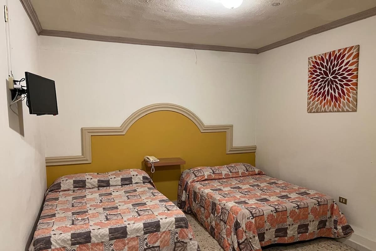 Ein Zimmer mit zwei Betten, einem Kopfteil, einem an der Wand montierten Telefon und einer Wanddekoration.