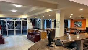Un vestíbulo de hotel con mostrador de recepción, zona de estar y puerta de vidrio de acceso.