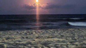 Une plage au coucher du soleil, avec des vagues et un ciel dégagé.