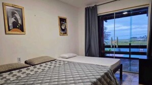 Une chambre avec un lit, une fenêtre donnant sur un beau paysage et deux tableaux encadrés accrochés au mur.