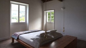 A bedroom with a wooden bed, two windows, and a hanging light fixture.