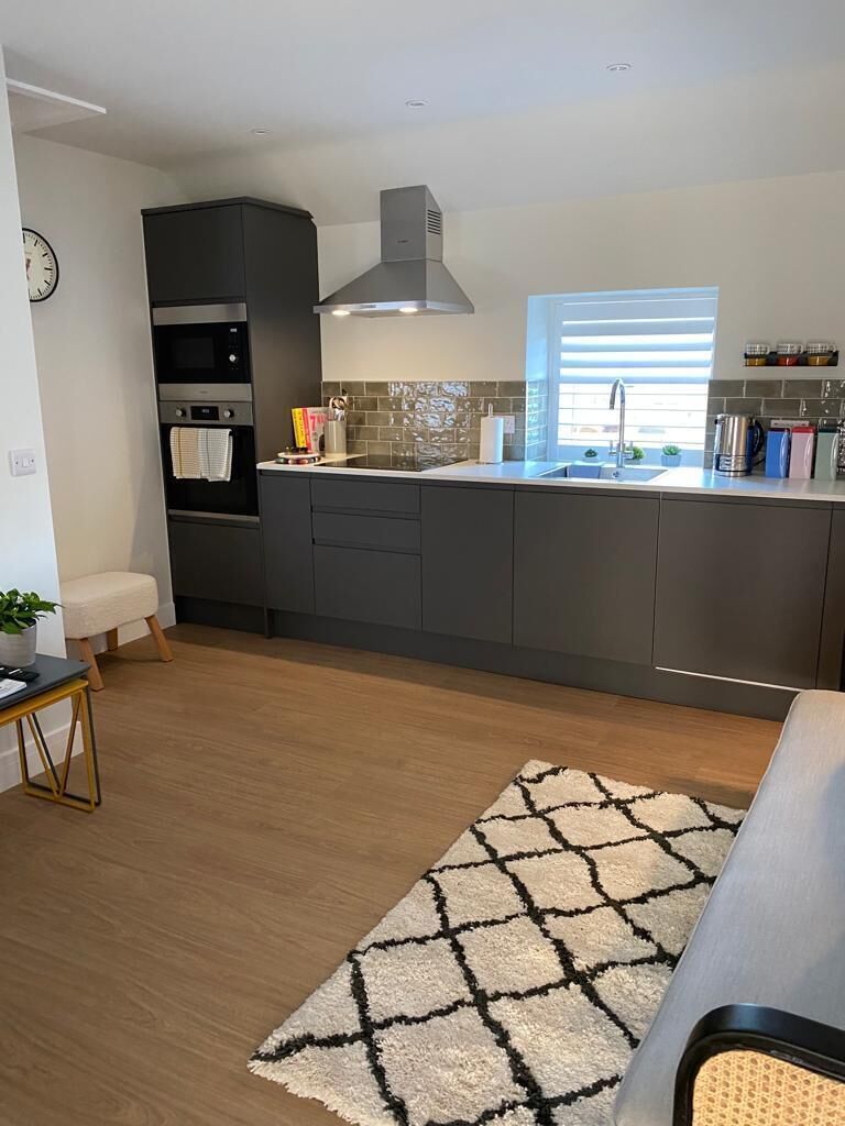 A modern kitchen with dark cabinetry, a built-in oven, and a window above the sink.