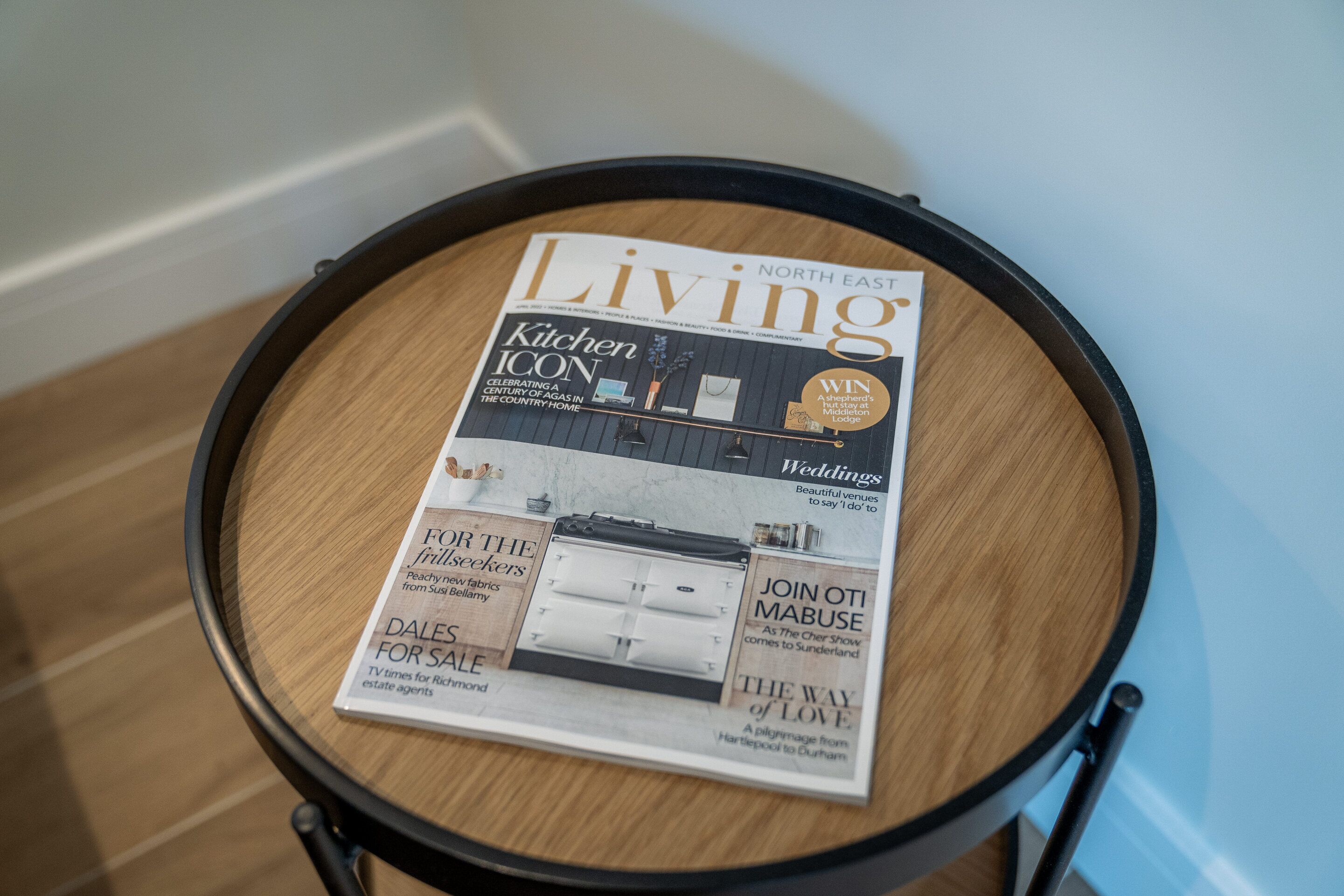 Una revista titulada 'Living' sobre una mesa redonda de madera.