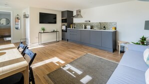 Eine moderne Küche mit grauen Schränken, einem eingebauten Ofen und einer großen Kücheninsel.