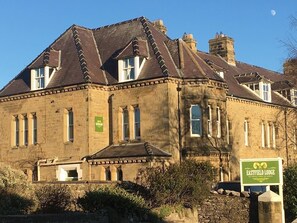 Ein historisches Gebäude mit einer steinernen Fassade, zahlreichen Fenstern und einem grünen Schild, das Eastfield Lodge anzeigt.