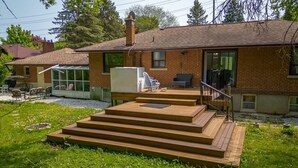 A two-story brick house with a deck, outdoor seating, and a large window. - home away home  (Toronto)