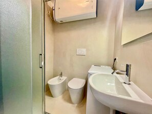 Ein Badezimmer mit einer Bidet-Einrichtung, Toilette und Waschbecken.